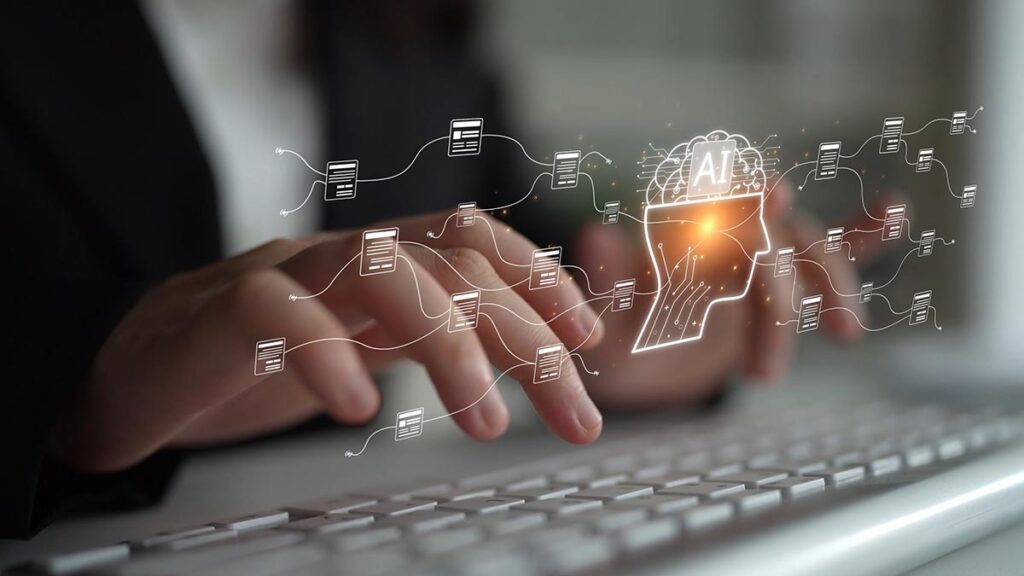 Close-up of a person's hands typing on a modern silver computer keyboard, with a digital overlay illustrating Artificial Intelligence. The overlay features a glowing white outline of a human head with a brain containing the letters "AI," connected by thin, flowing lines to various digital document icons, symbolizing data processing and automated content generation.
