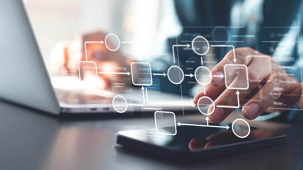 Professional using digital software for business process mapping and agile workflow management on a laptop and mobile device.