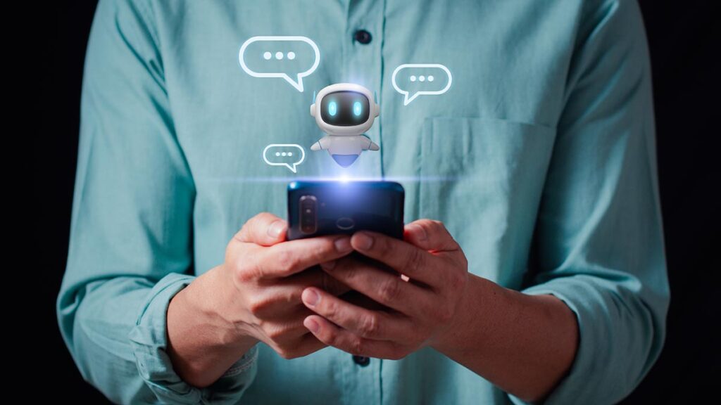 A person holds a glowing smartphone in their hands. A small, white digital robot character hovers above the screen, surrounded by three floating speech bubble icons, representing an AI chatbot in a messaging or customer service app.